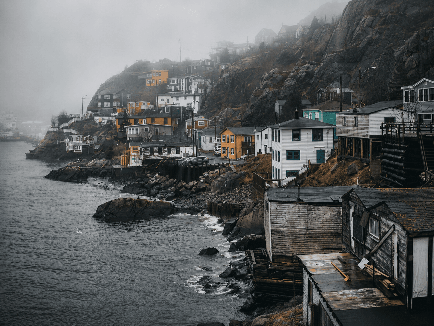 Fog settling over a colourful Newfoundland coastal community beside the Atlantic.