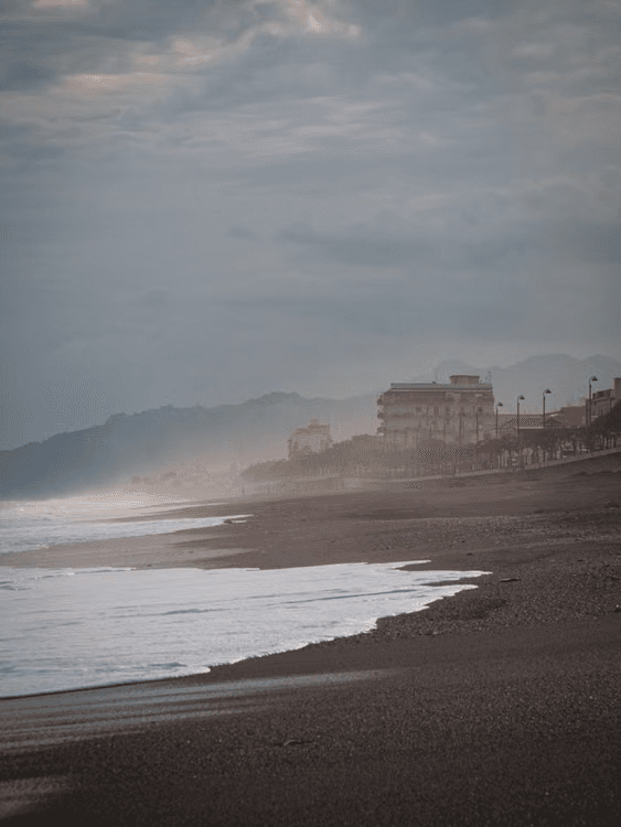 A quiet Mediterranean shoreline in hazy shoulder-season weather.